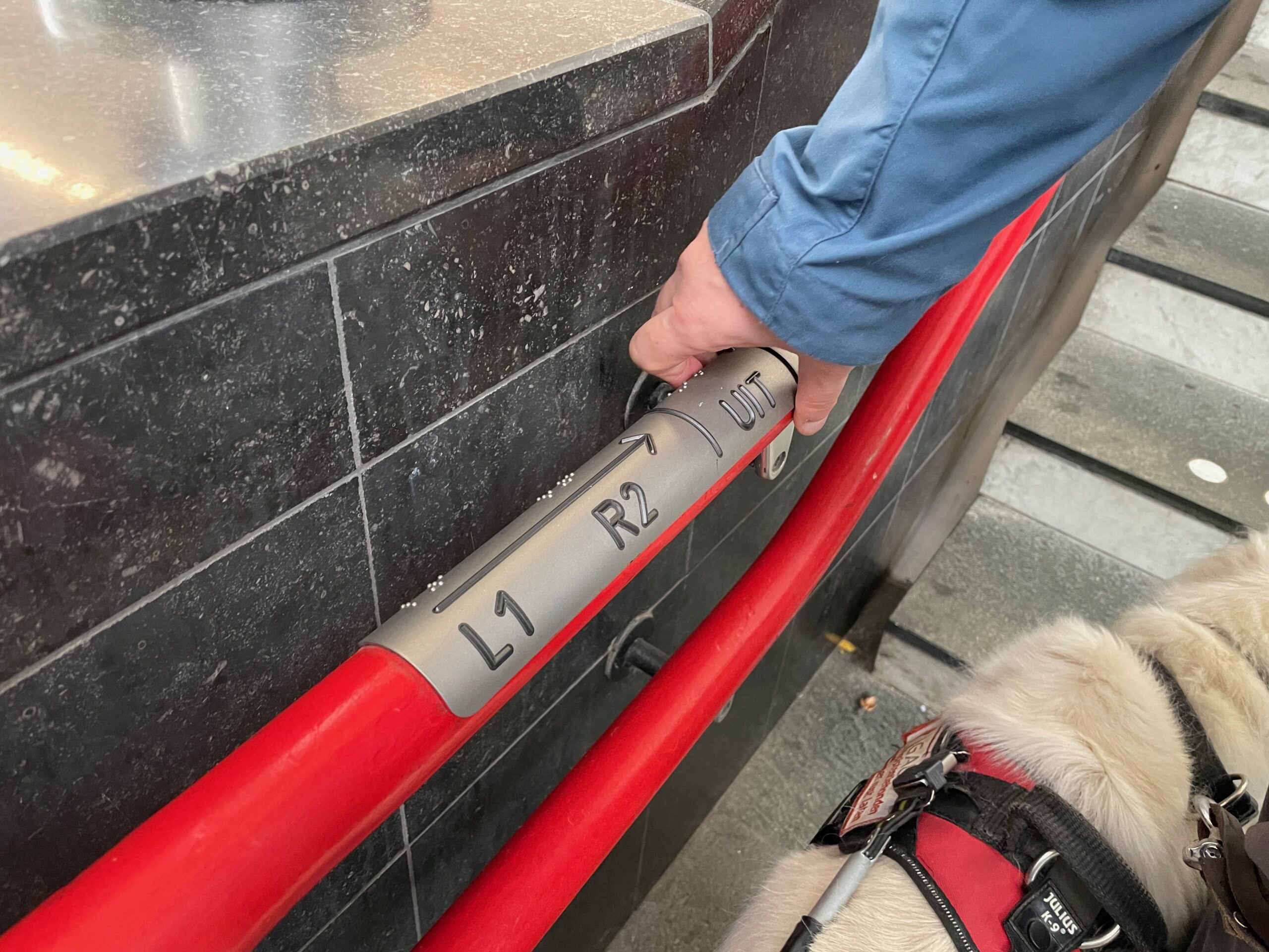 Op de armleuning bij de trap staan aanwijzingen in braille.