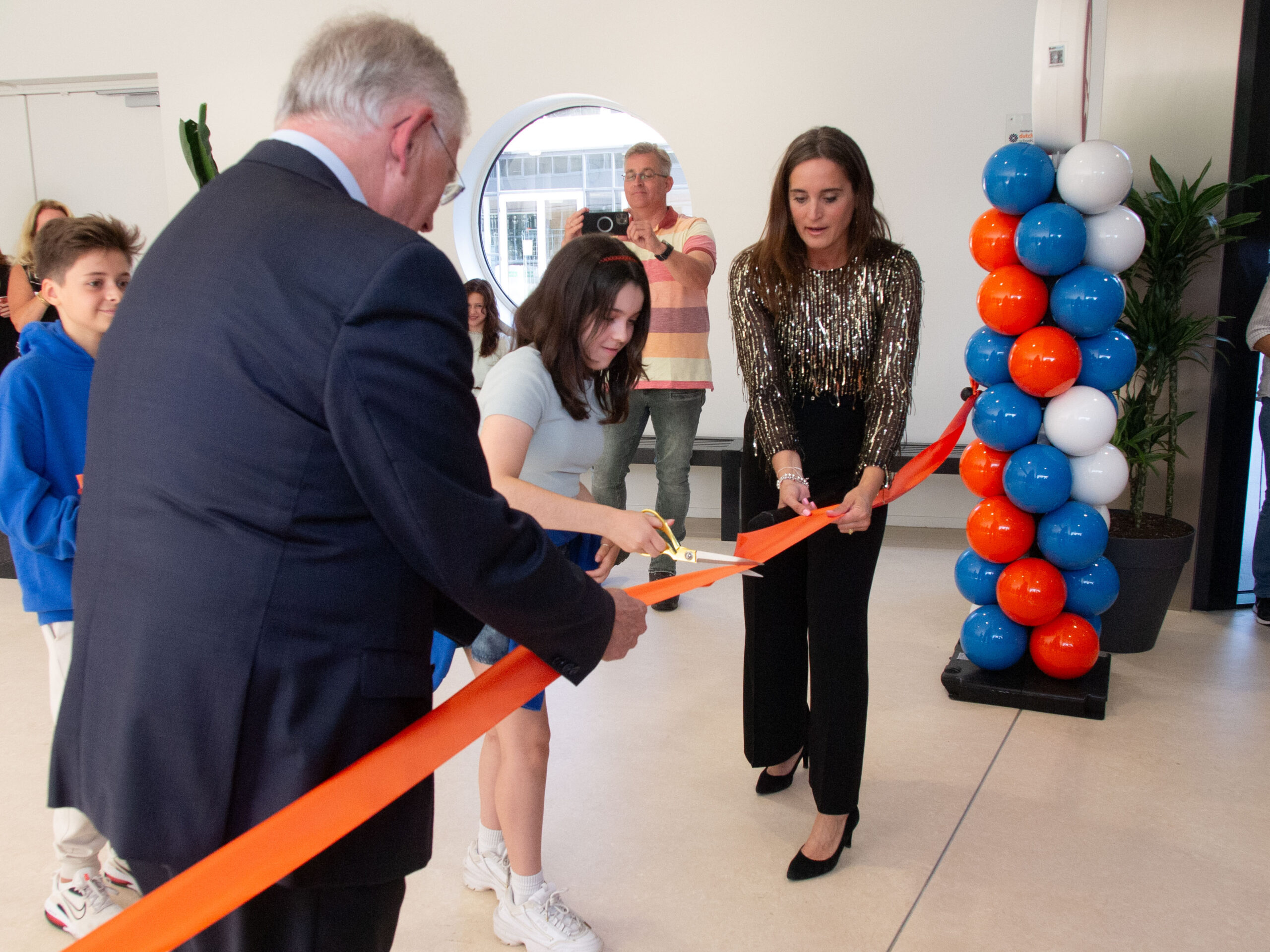 Wethouder Ritske Bloemendaal, rector Wendy Groen en leerling knippen lint symbolisch door