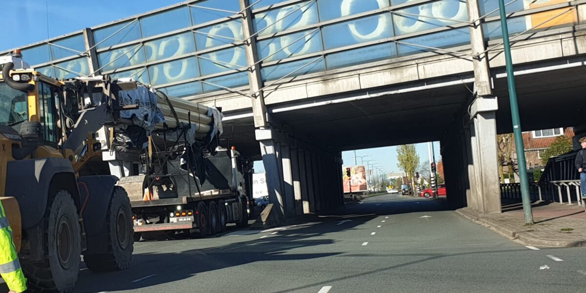 Vrachtwagen met buizen vast onder viaduct